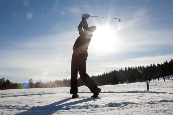 Golfer teeing off in snow